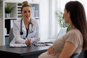 A gynecologist is consulting with a pregnant patient in the clinic prior to a pediatric gynecology exam.